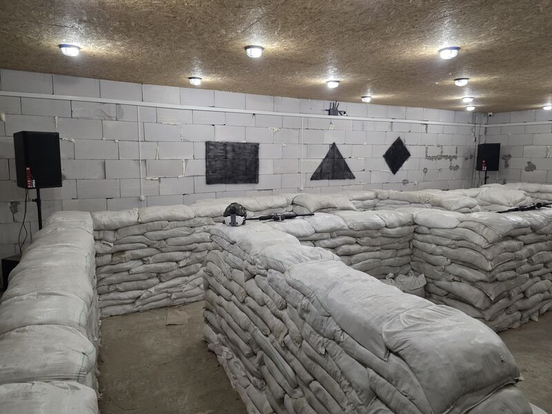 Training bay with sandbag lanes, geometric targets, and immersive speaker system